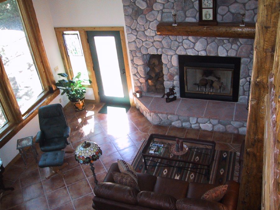 Loft overlooks logs and stone fireplace